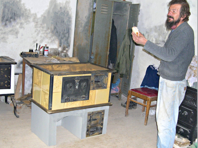 Kachliar Jozef Pekarík na „svačine“ pri prenosnom šporáku s klenbou, s podkovou na radiátory