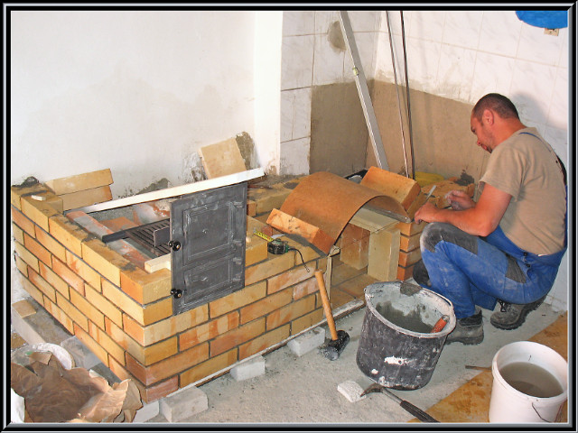 kachliar pri práci uvedeného šporáku v Madačke