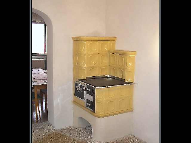 Stolový šporák, ktorý prechádza cez stenu, kde týmto vykuruje ďalšiu miestnosť